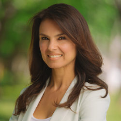 A woman with medium-length brown hair, wearing a white suit and top